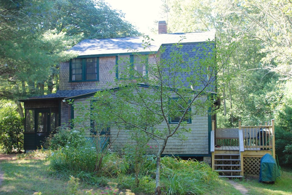 Side view from parking area showing back deck, grill and front porch.