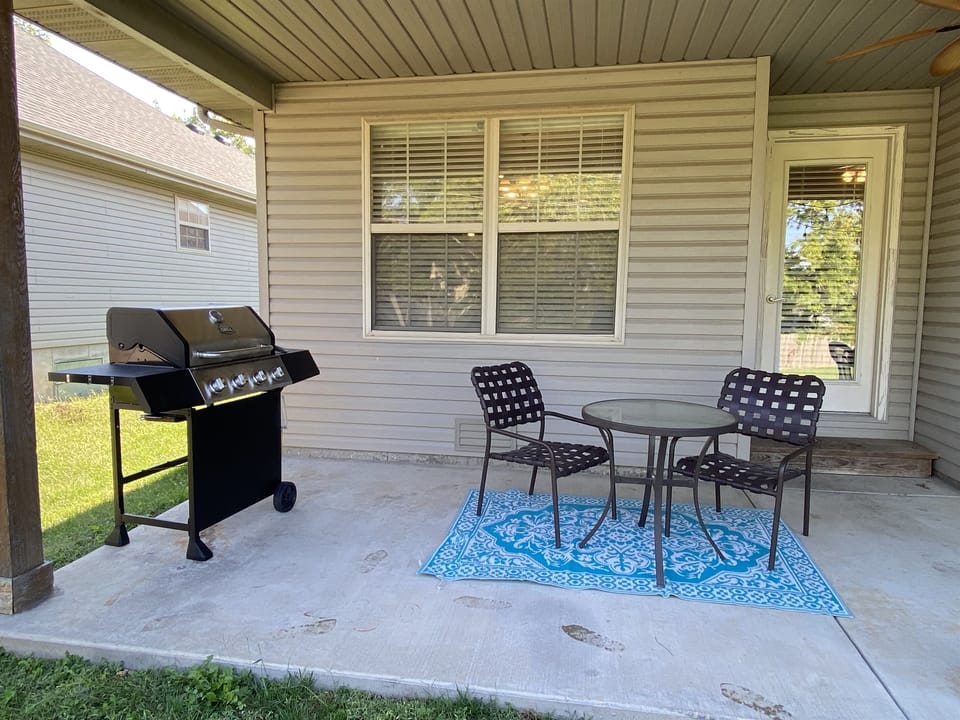 Lighted back porch has a propane bbq grill, seating, & outdoor games.