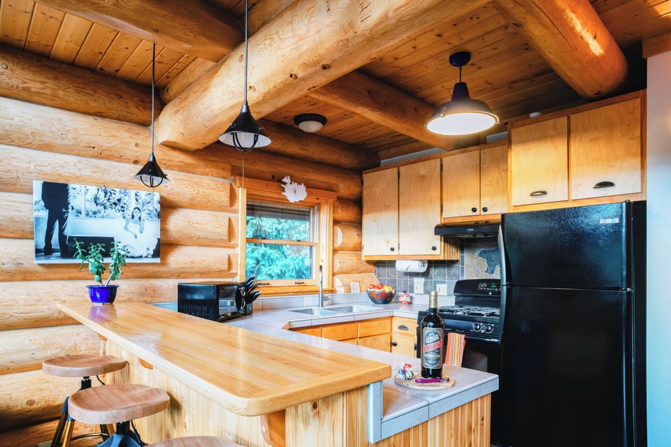 Kitchen with wood bar, swivel stools, and black appliances