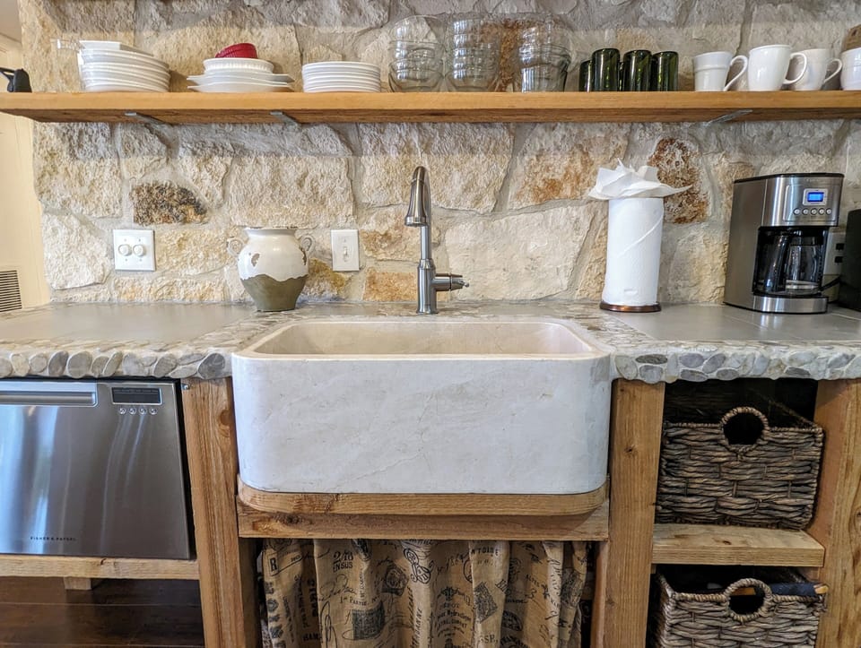 Limestone wall kitchen with marble sink and custom stone/pebble countertop.