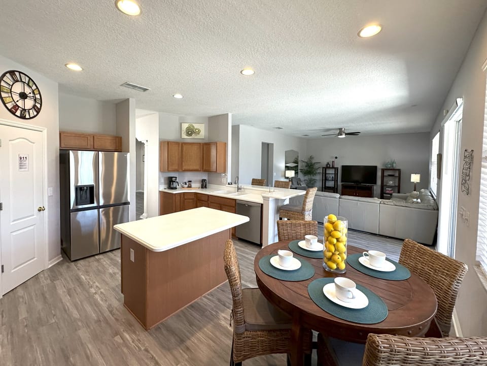Open plan kitchen with four seat breakfast table and three bar chairs