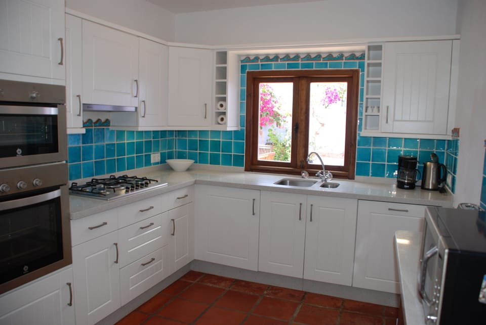 Fully fitted kitchen windows open onto patio.