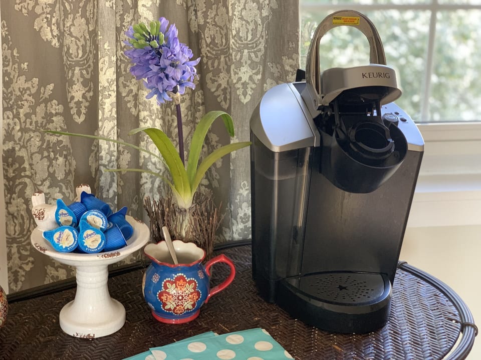 Keurig coffee maker with coffee, creamer, sweetner, & sugar.