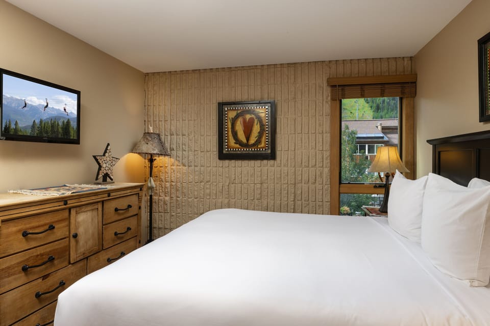 Sink into crisp white linens and rustic wood furnishings in your cozy retreat. Wake to mountain scenery through the window and unwind with warm lamplight illuminating textured walls that whisper mountain lodge charm.