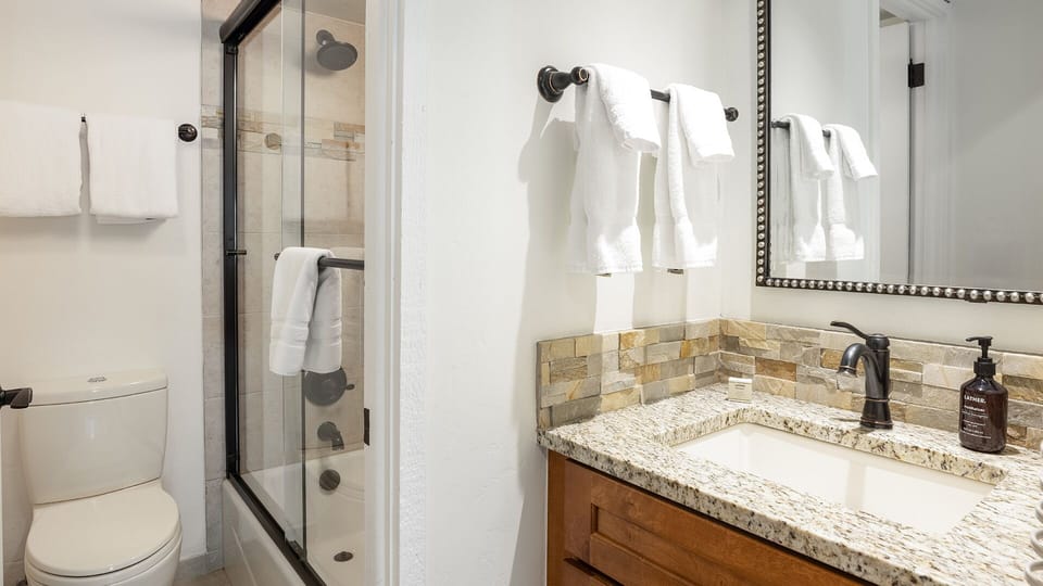 Your private bathroom features a granite vanity, glass-enclosed shower, and crisp white towels—everything you need to refresh after a day of exploring.