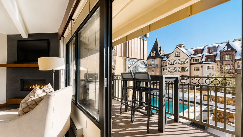 Step into your cozy retreat where a warming fireplace invites relaxation, and your private balcony opens to stunning village views and poolside scenery—perfect for morning coffee or evening unwind.