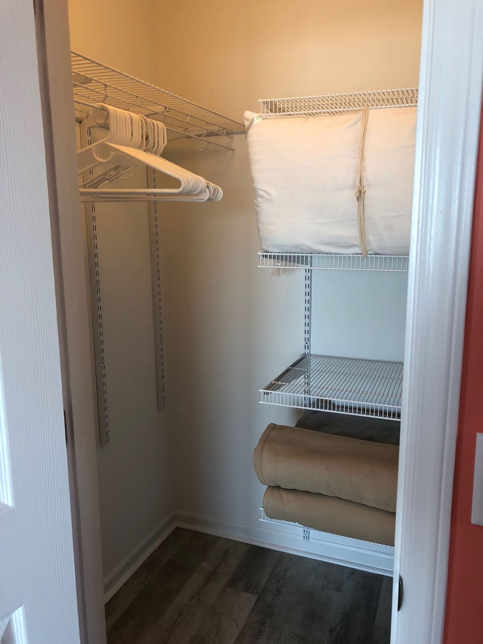 The walk-in closet has hanging rods & shelves,  more pillows & blankets as well