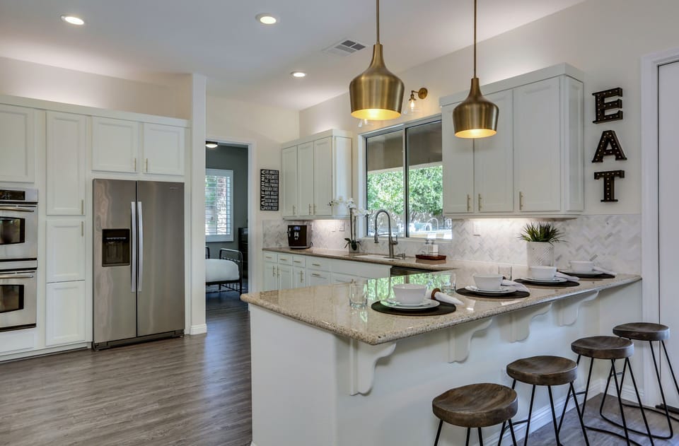 Remodeled kitchen with stainless steel appliances, granite countertops, double oven and marble chevron backslash for a fun and inviting feel