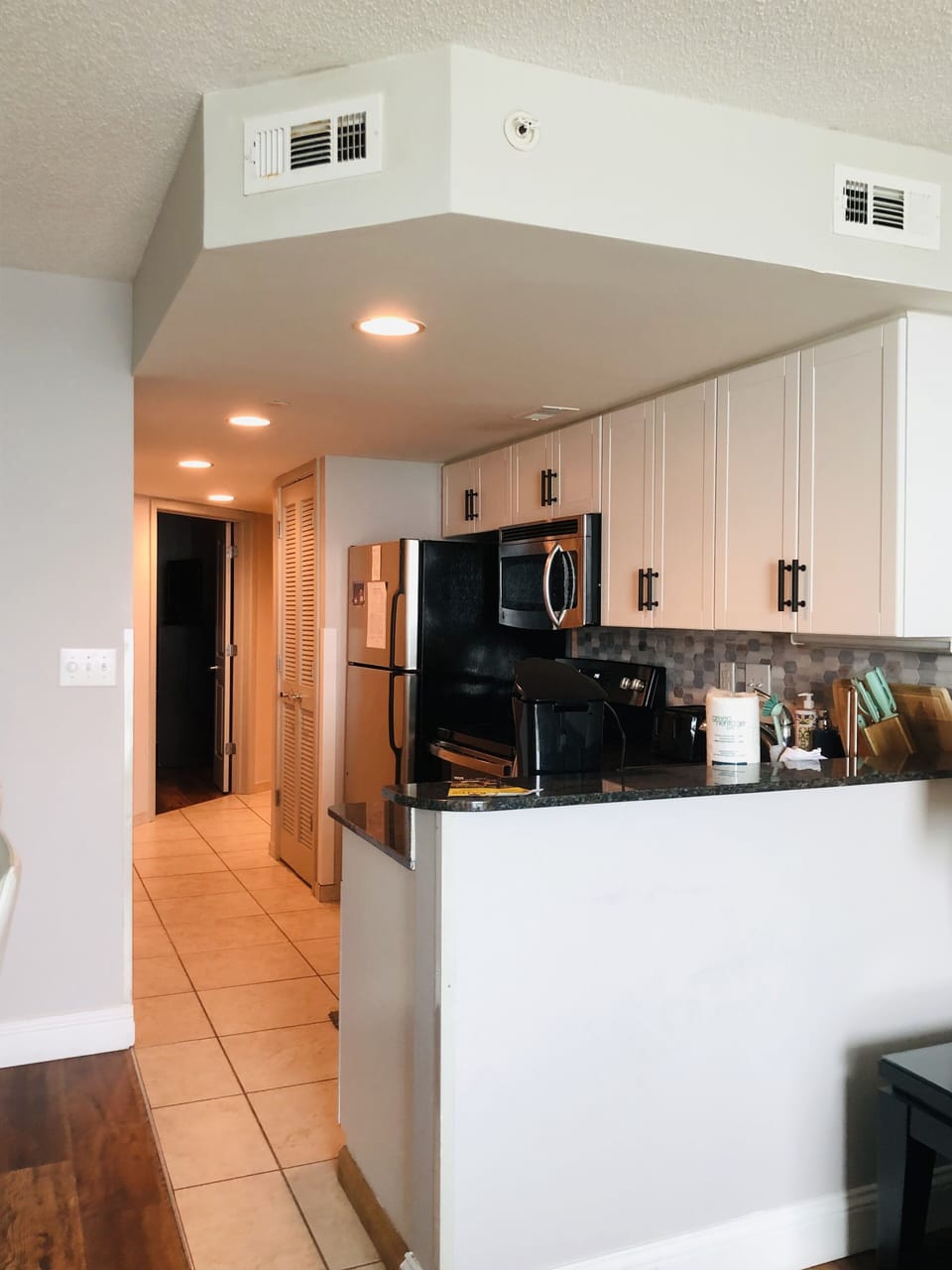 Cozy kitchen with modern appliances, black countertops and white cabinets.