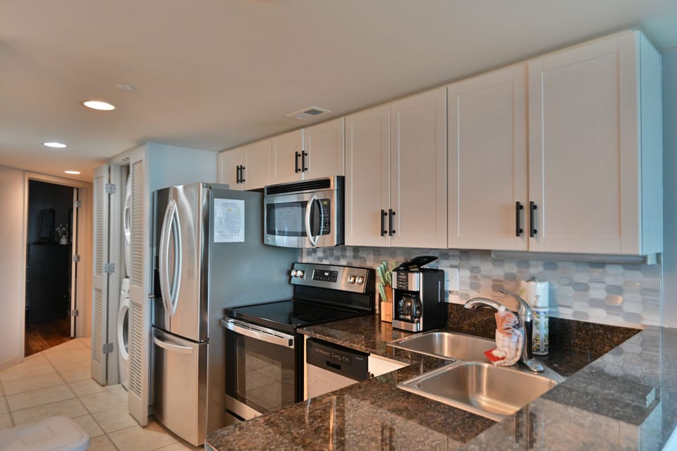 A modern kitchen featuring stainless steel appliances, white cabinets.