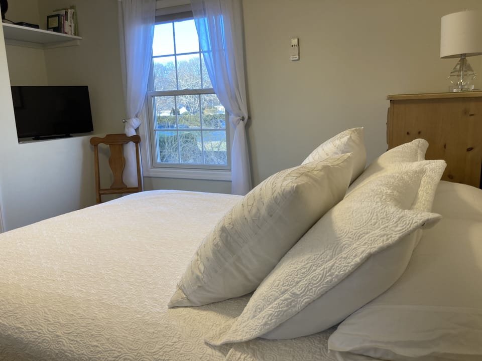 Queen size bed with white 100% cotton sheets, linens and down & feather pillows.