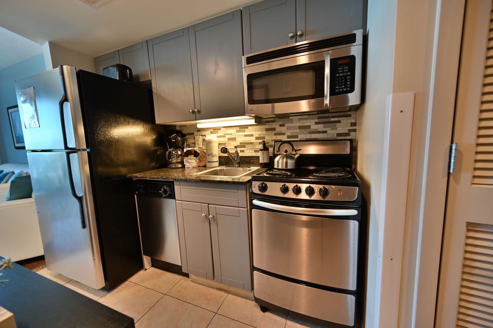 Modern kitchenette with stainless steel appliances, stylish backsplash