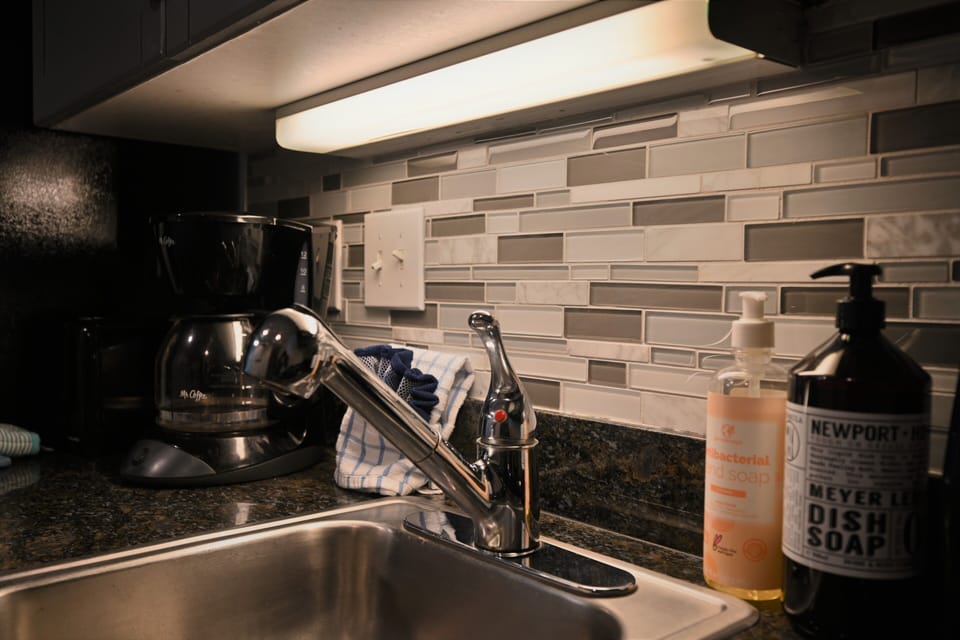 Stylish kitchen with modern backsplash, under-cabinet lighting, and sink area.