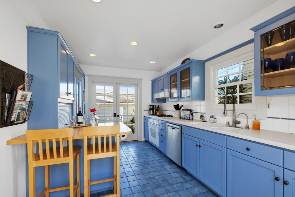 Sunny kitchen with breakfast bar and doors to back lounging area.