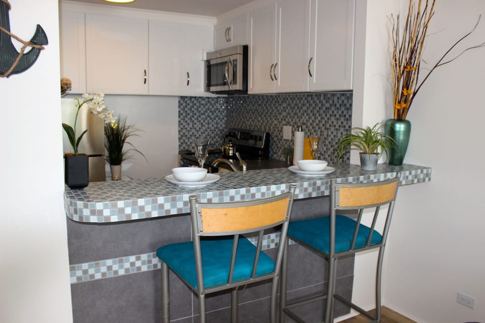 A bar-top with two bar stools to match, a fully-stocked kitchen 
