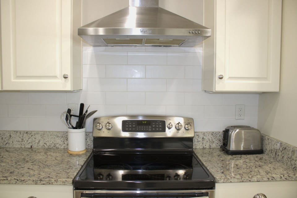 Sleek stainless steel stove with a modern range hood and granite countertops!