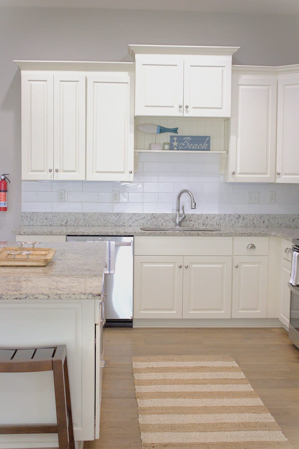 Bright, coastal-style kitchen with white cabinets, granite countertops, and a beachy touch!