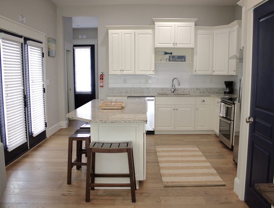 Bright, cozy kitchen with white cabinets, granite counters, and coastal touches!