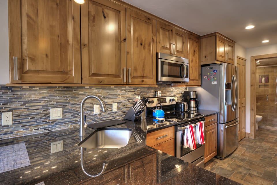 Brand new, modern and sleek kitchen, with bar stools for two at end.