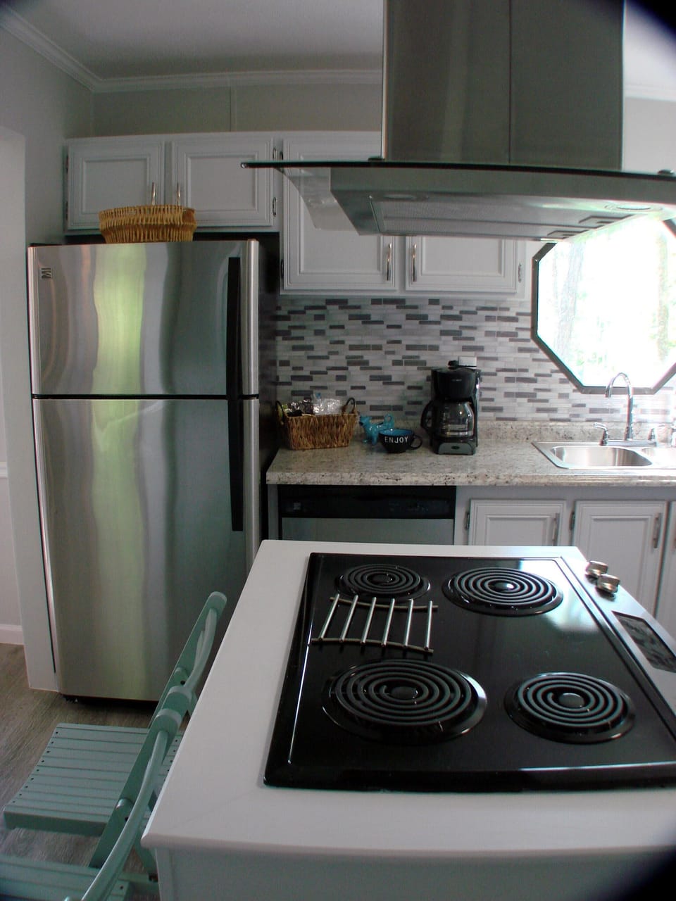 View of new stove, range hood, refrigerator and sink with lake view. 