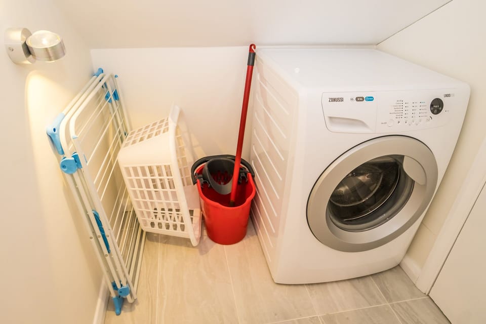The washing machine is located in a cupboard upstairs.