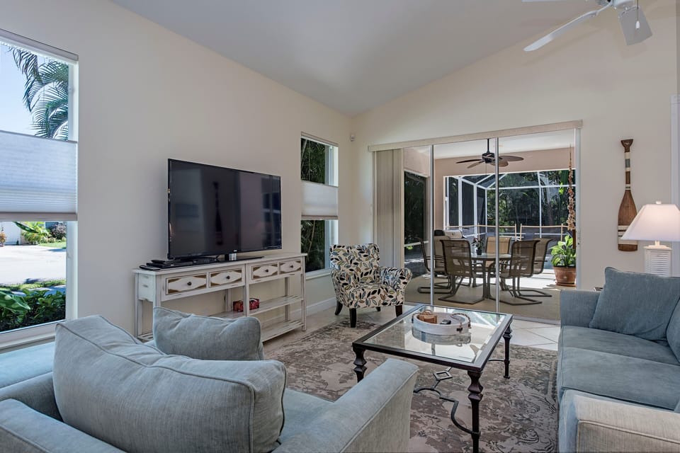Great room w/ 60 inch tv, top down bottom up shades on windows & sliders to pool