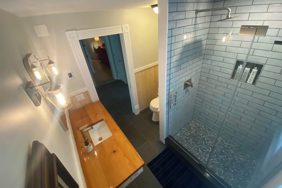1st Floor Bathroom: custom floating wood vanity with glass shower enclosure and rain shower head.