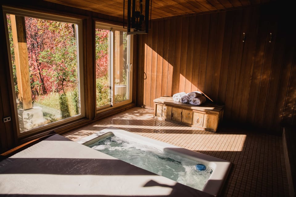 Hot tub room with windows and doors that open to outside.