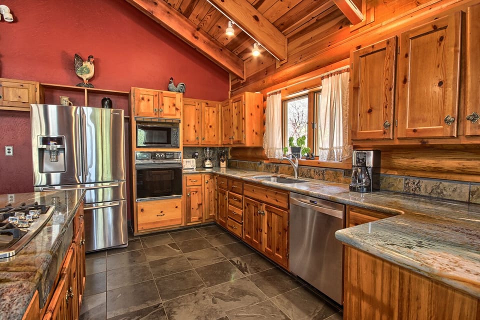 Rustic kitchen with wooden cabinets and a large granite island, warmly lit.