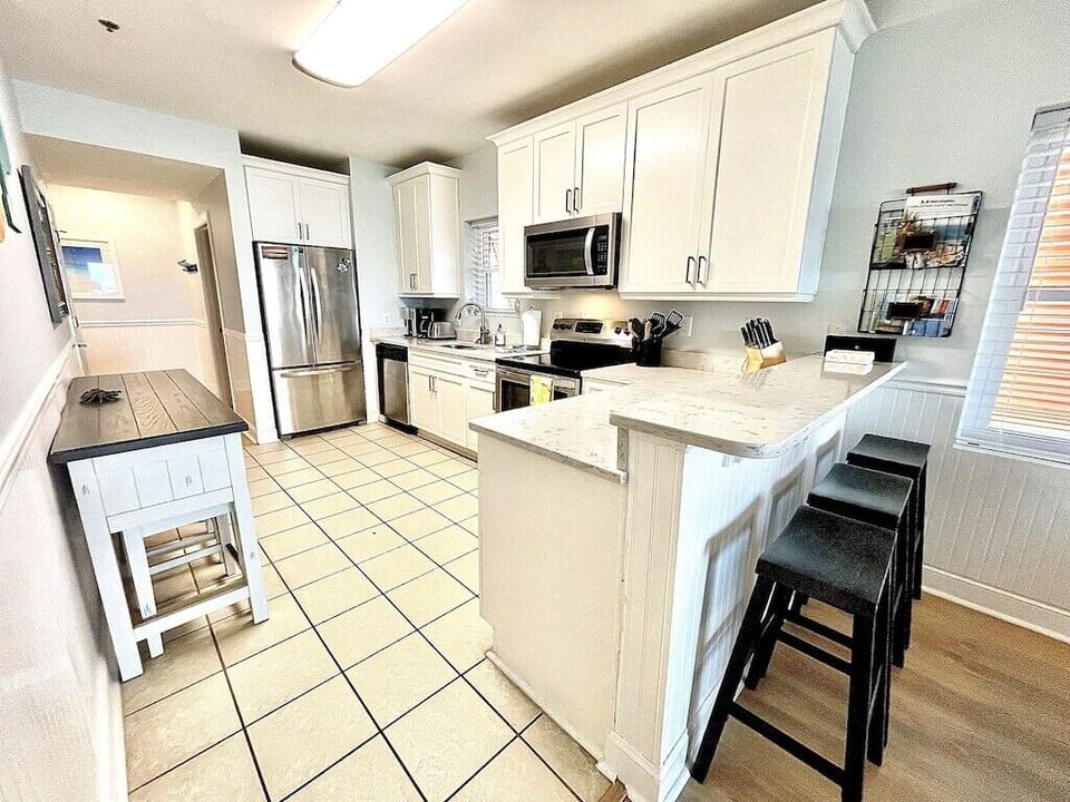 Kitchen with stainless steel appliances and prep island with seating. Oceanview, 201 Isle of Palms, SC | IOP Escapes