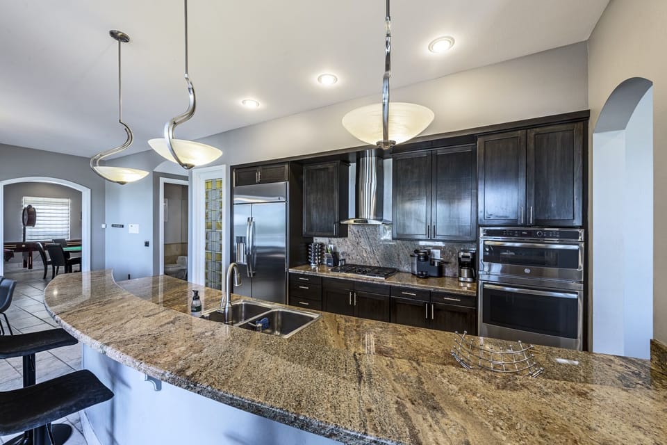 Kitchen with large 48" wide fridge, oven, range hood, large breakfast bar.