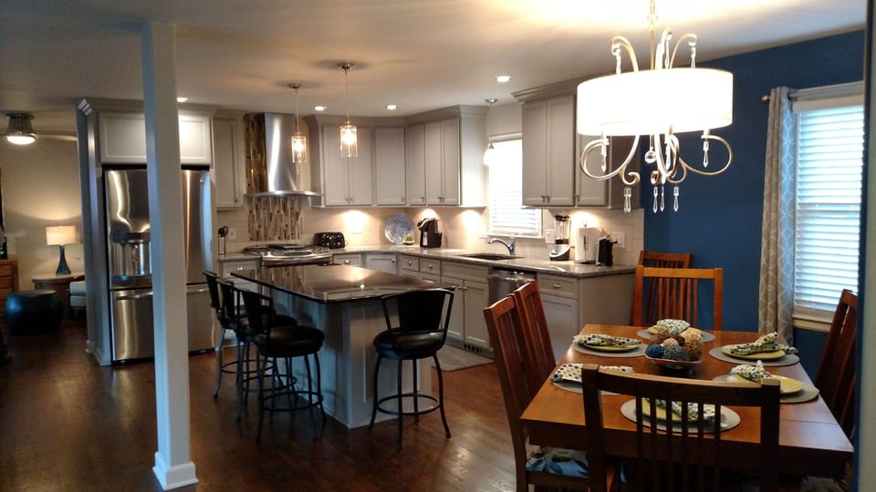 View of dining table and chairs next to open kitchen.