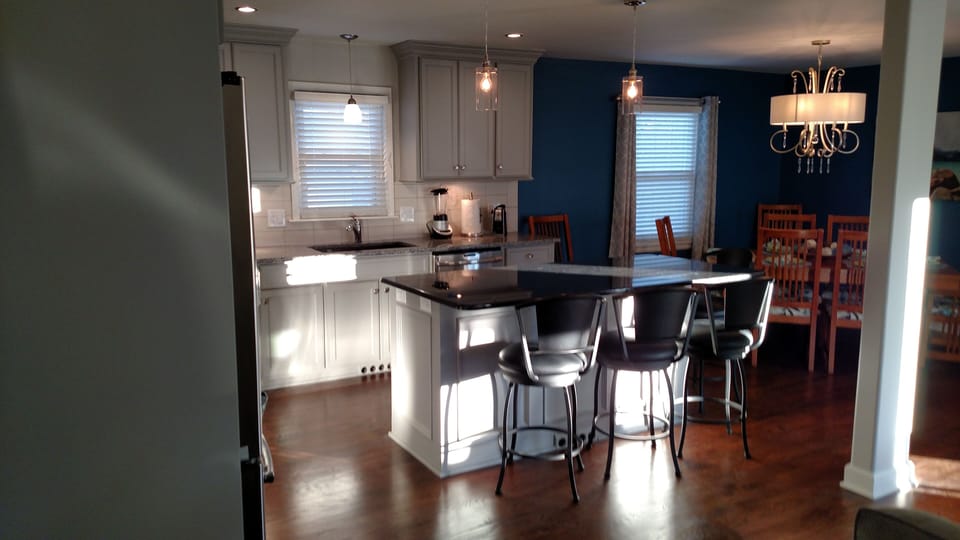 View of open kitchen with kitchen island and stools and dining set right behind.