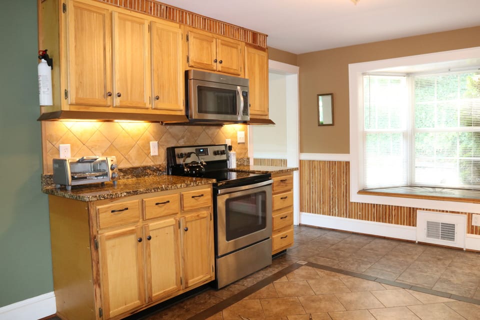 Kitchen showing stove/oven, toaster oven, microwave, counter space & bay window