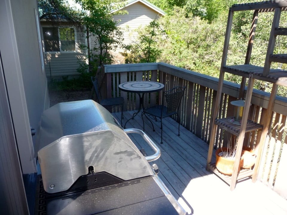 Back deck with a small table, chairs and BBQ.  Stairs lead to the hot tub.