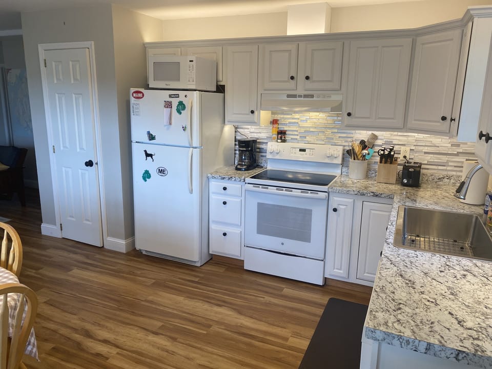 Well lit kitchen with stocked cookware and new appliances 