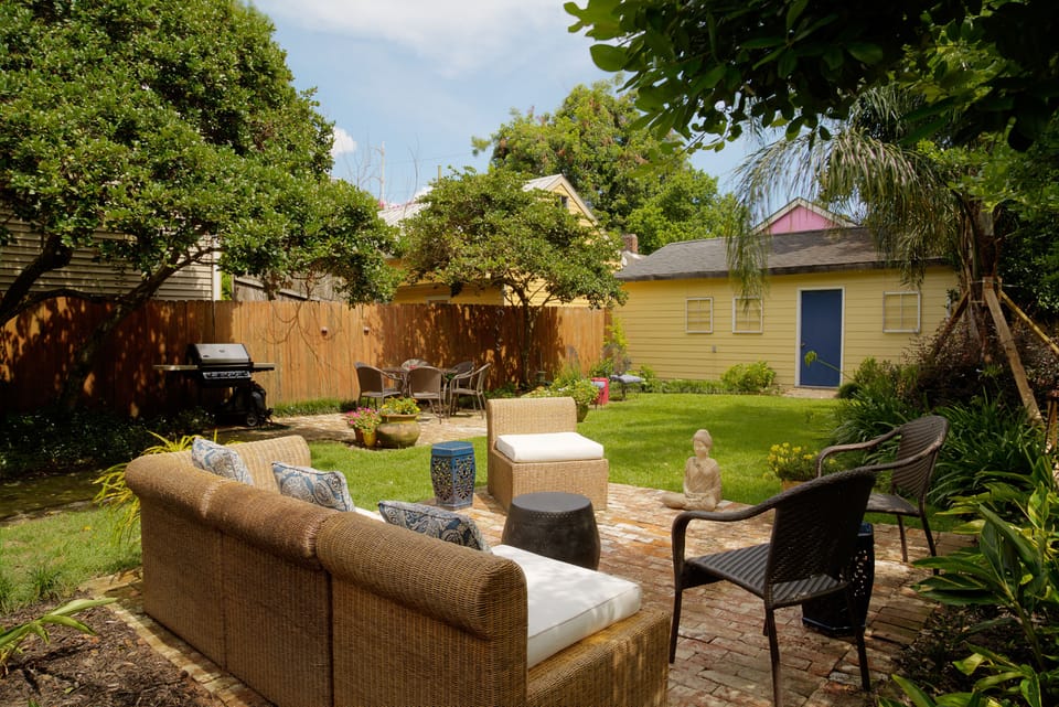 two patios in the back garden with a gas grill. The yellow building is storage