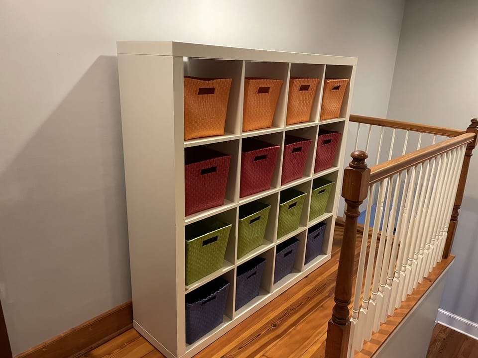 Hallway cubby storage has books and toys for children.