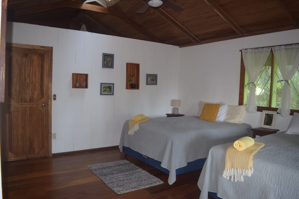 Bedroom on main floor with 2 queen beds, private entrance to bathroom & balcony.