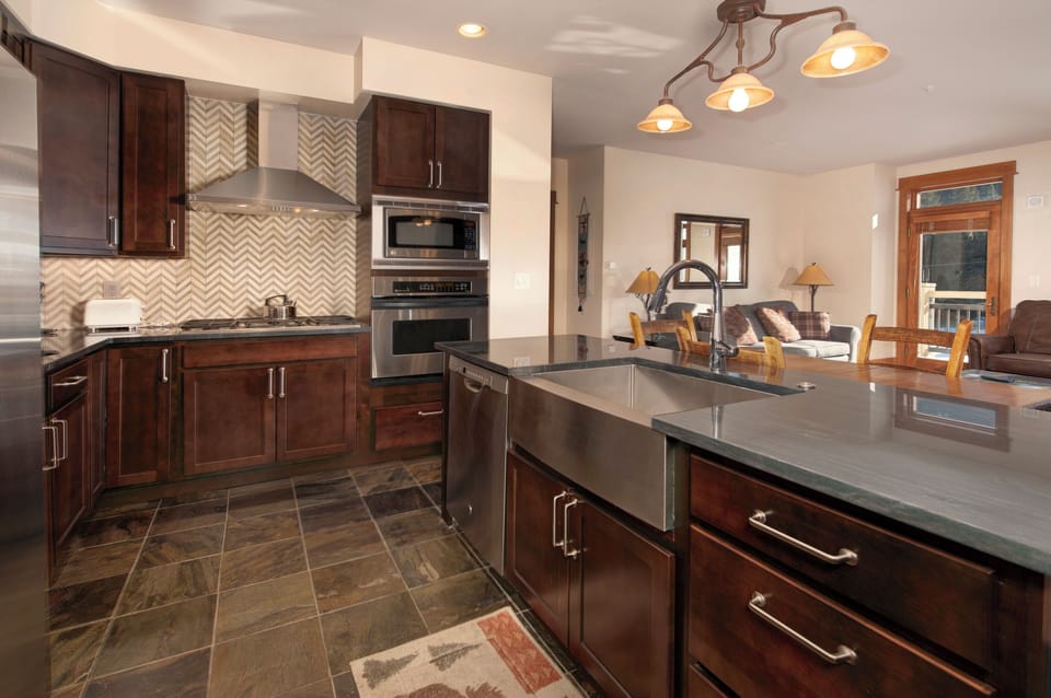Kitchen with stainless steel appliances, granite countertops, slate tile floor.