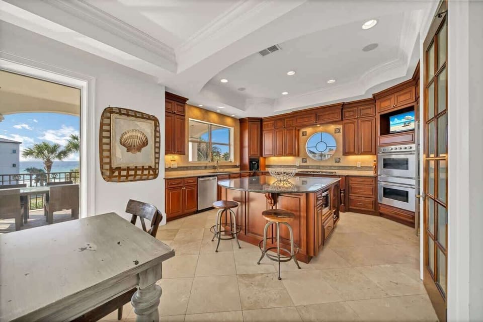 This Huge Kitchen Features Double Wall Ovens, A LArge Fridge and Freezer Combo and  5 Burner Stove Top All Surrounding The Massive Kitchen Island