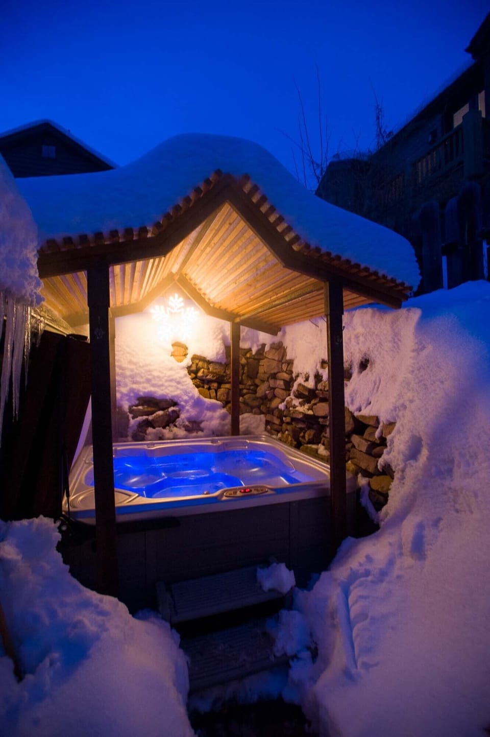 Hot tub in backyard grotto with soothing lighting.