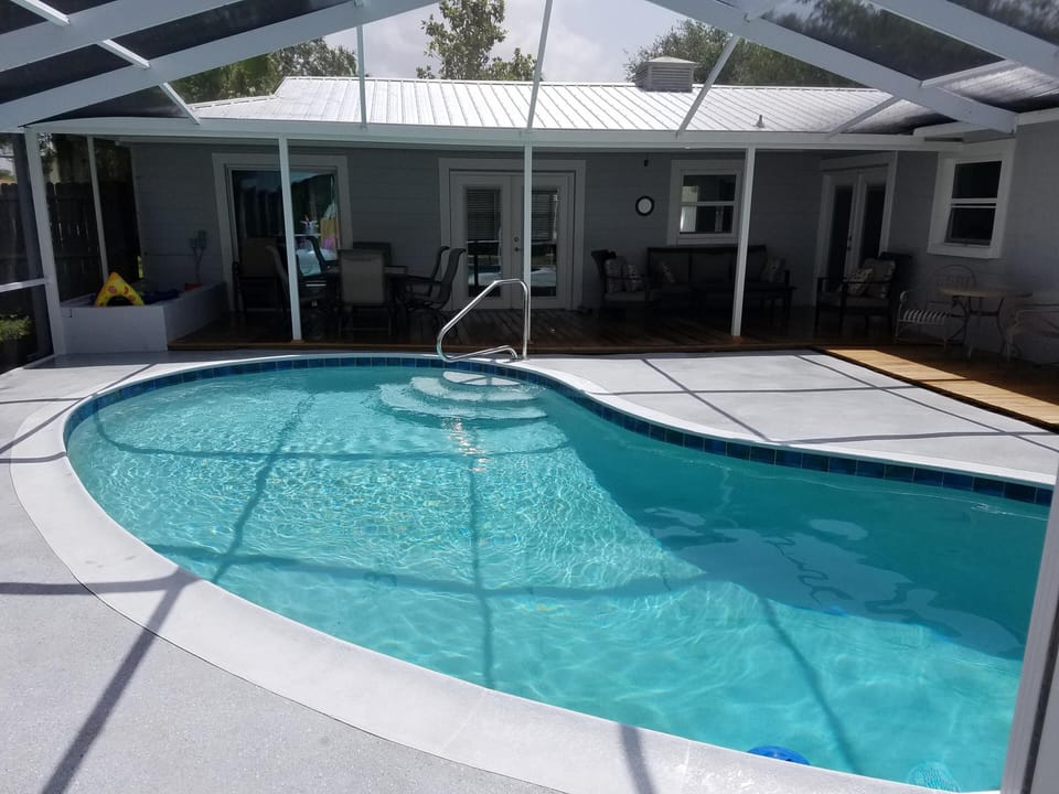 Pool looking to back porch with table to left and large seating area to right