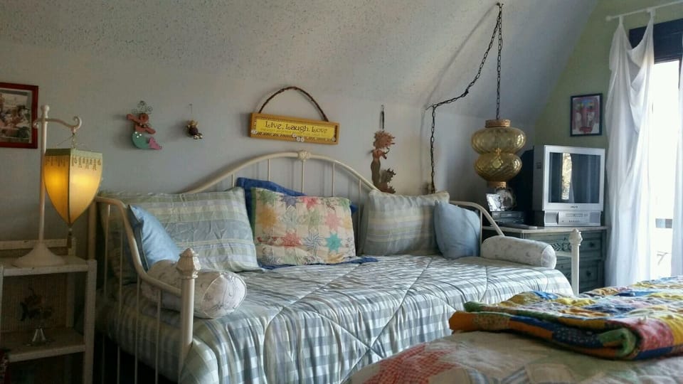 Upstairs lakeside bedroom has a daybed and a queen. Seating, closet and balcony.