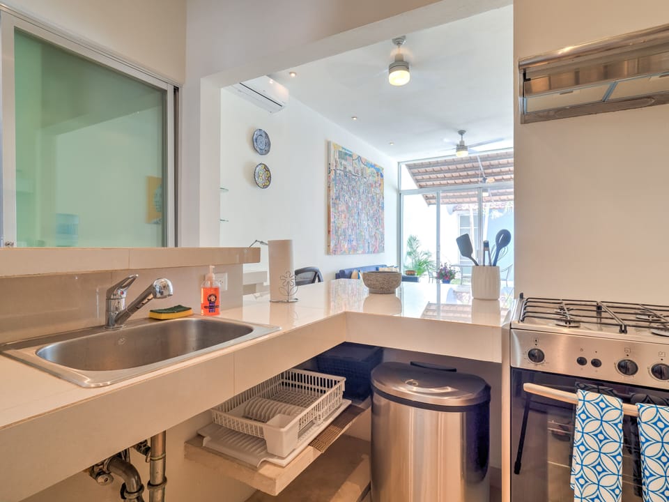 Kitchen stocked with cooking essentials including pots/pans, S&P, olive oil.