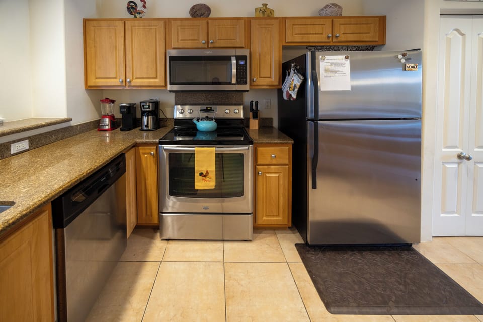New stainless steel appliances with cabinets stocked with dishes and glassware
