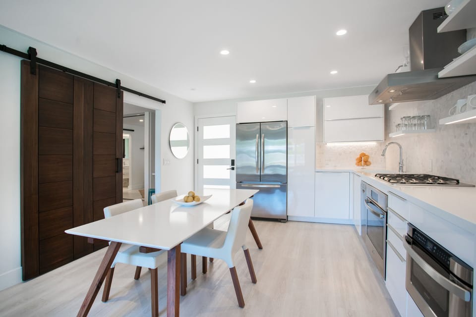 LARGE, CUSTOM QUARTZ & WALNUT TABLE.   REVEALS SLIDER BARN DOOR TOWARD BEDROO