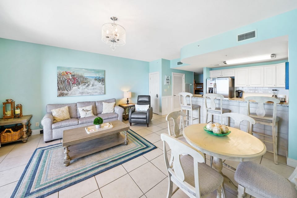 Your spacious coastal retreat awaits with soothing turquoise walls, comfortable living area, and fully-equipped kitchen perfect for family meals.