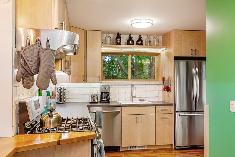 Kitchen includes a vented range hood, gas range, coffee maker, coffee press, coffee grinder, coffee filters, toaster, blender, garbage disposal, microwave, dishwasher, fridge, freezer, ice maker, and lots of kitchen and housewares. 
