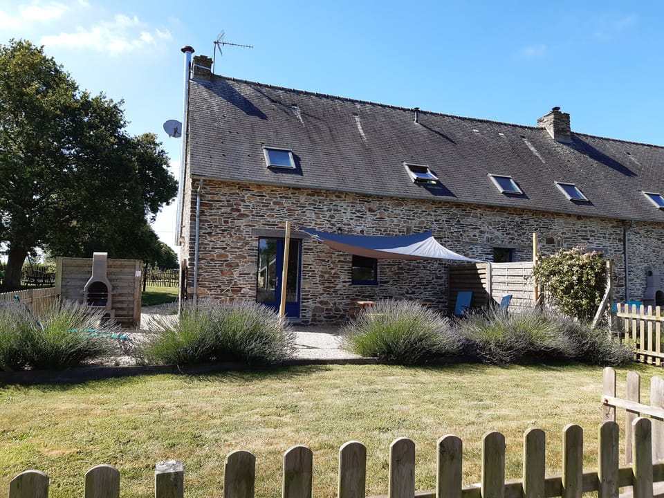 Jardin clos avec patio, voile d'ombrage, coin repas extérieur et barbecue.
